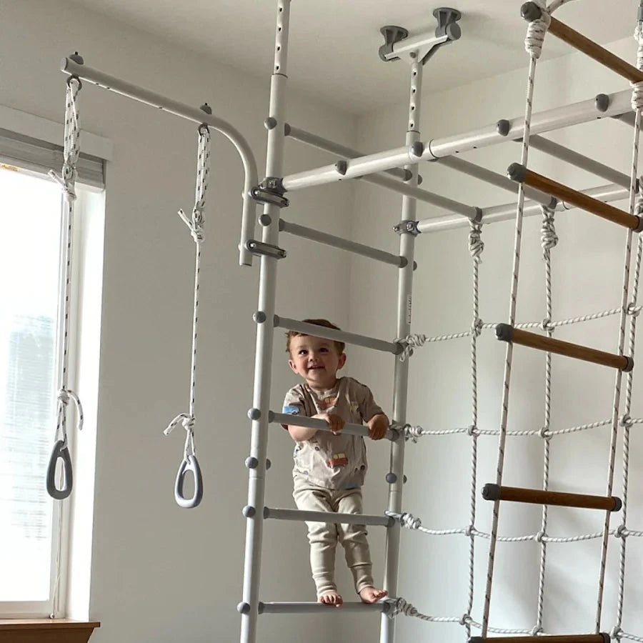 Child playing on a indoor play structure with ropes and ladders.