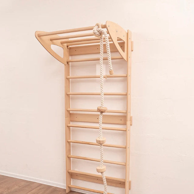 Wooden climbing ladder with rope on a white wall
