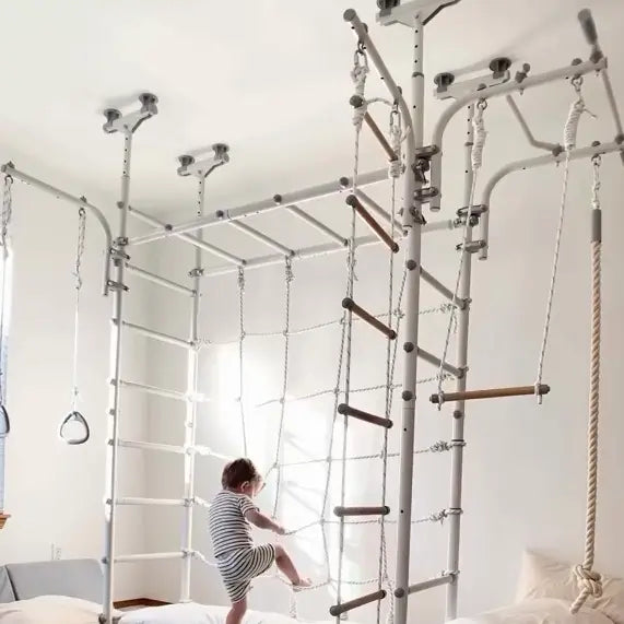 Child playing on a indoor play structure with ropes and ladders in a room.