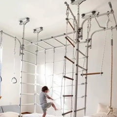 Child playing on a indoor play structure with ropes and ladders in a room.