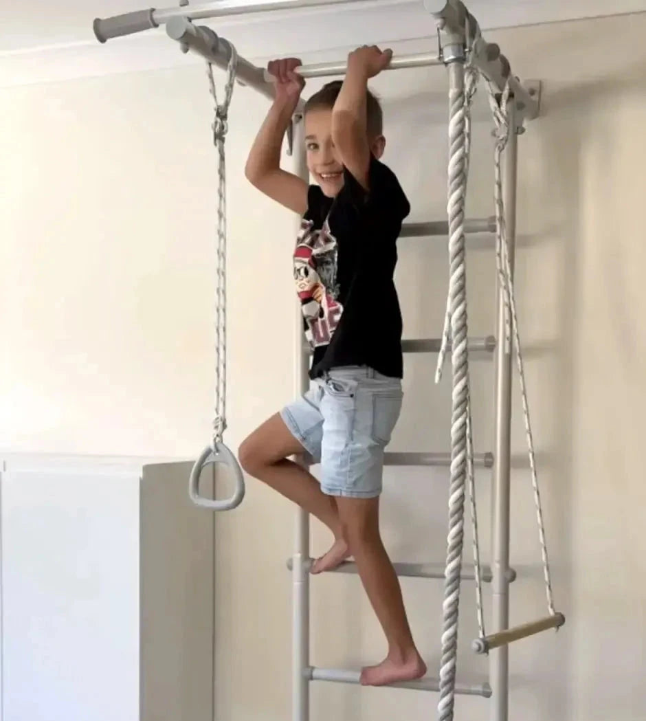 Child climbing on a metal ladder with rope in a room.