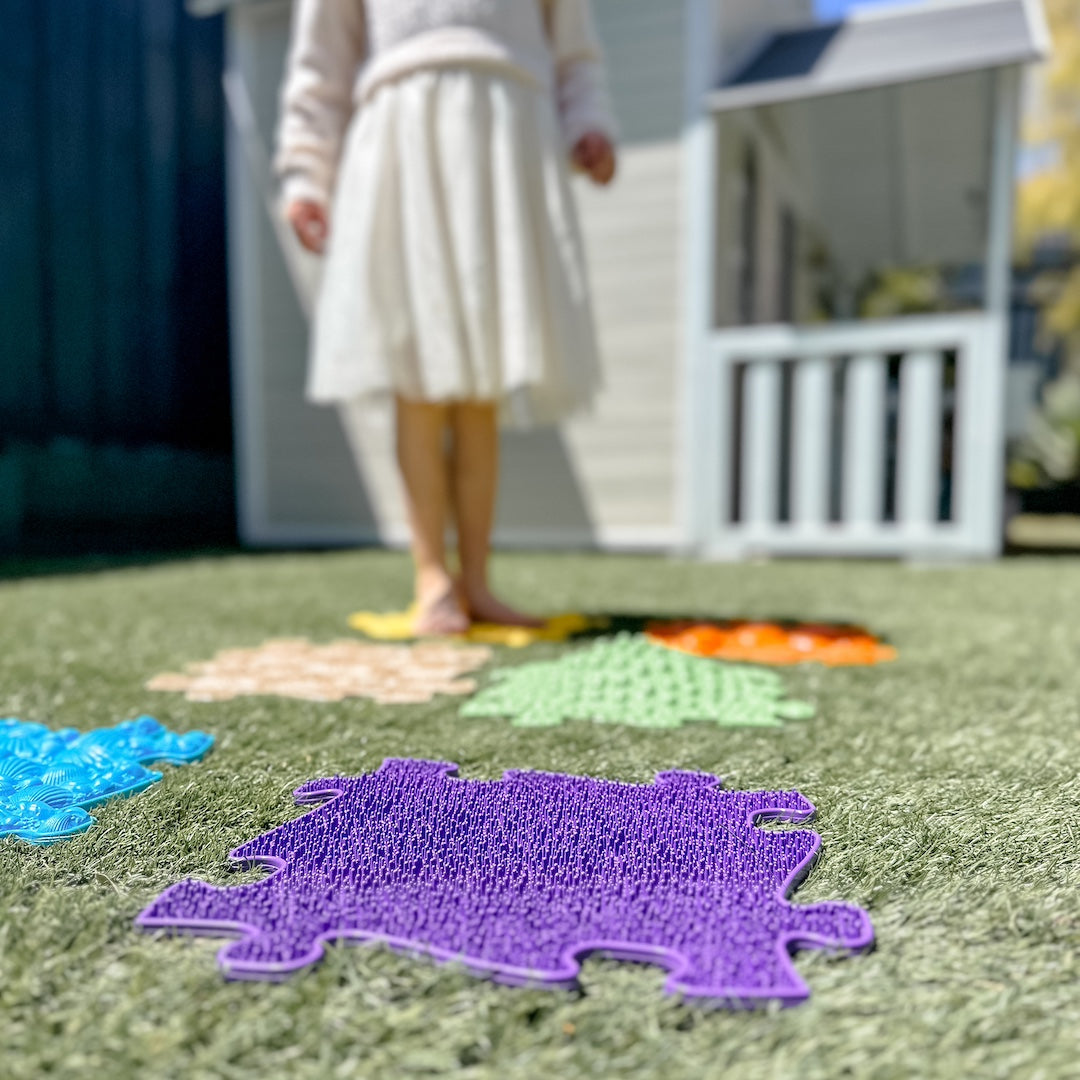 A colorful Muffik sensory puzzle piece backdrop with a girl in front.