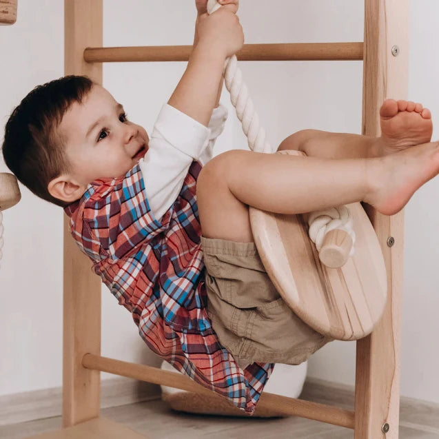 Child playing on a wooden climbing toy indoors