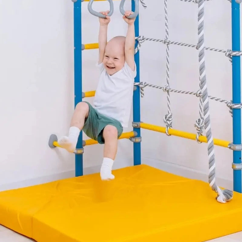Child playing on a playground structure with yellow padding