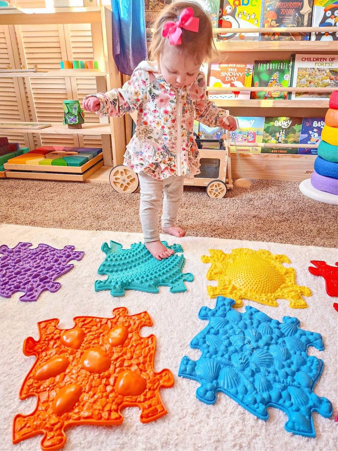 a toddler standing on sensory tactile mat which is in rainbow colour. There are 8 pieces in this set