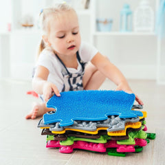 girl holding a set of sensory playmats by Tinnitots